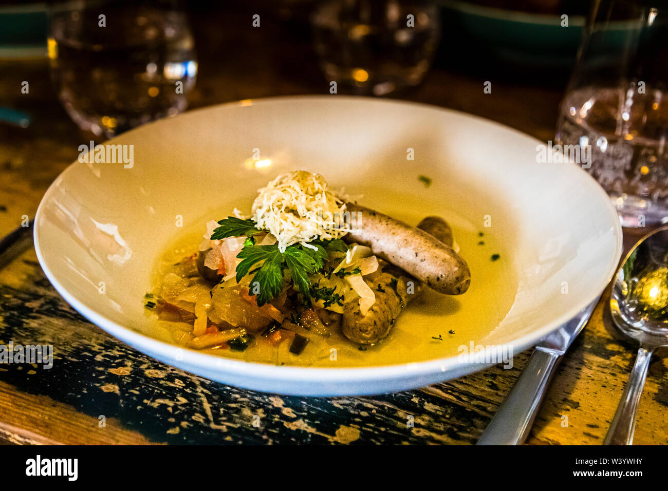 'Blaue Zipfel', una coppia di salsicce francone pochate in un brodo di aceto con cipolle e servite qui con ravanello grattugiato e prezzemolo al ristorante Schuberts a Bad Kissingen, Germania, deve il suo nome e la leggera sfumatura bluastra a quel brodo di aceto. Il piatto è un classico piatto principale della Franconia, tradizionalmente servito con pane o pretzel. Foto Stock