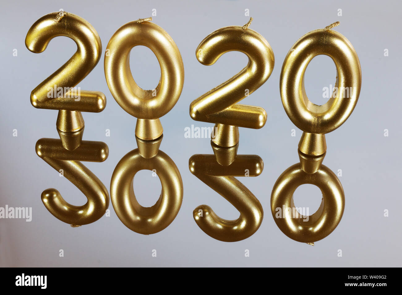 Candela oro sfondo per il 2020 anno. Candele su una superficie a specchio con la riflessione. Foto Stock