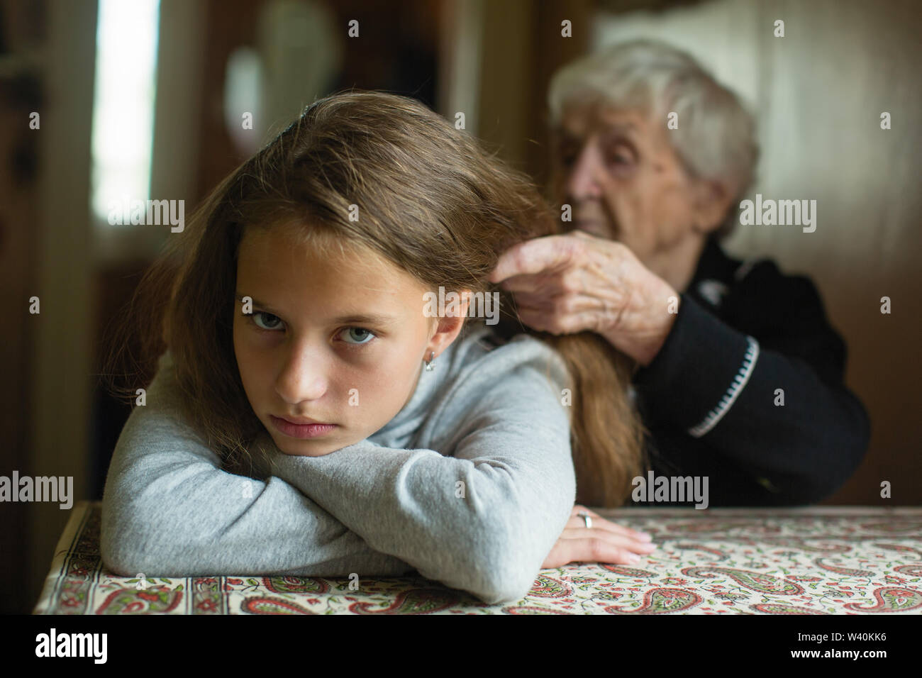 Una donna anziana trecce suo nipote di capelli. Foto Stock