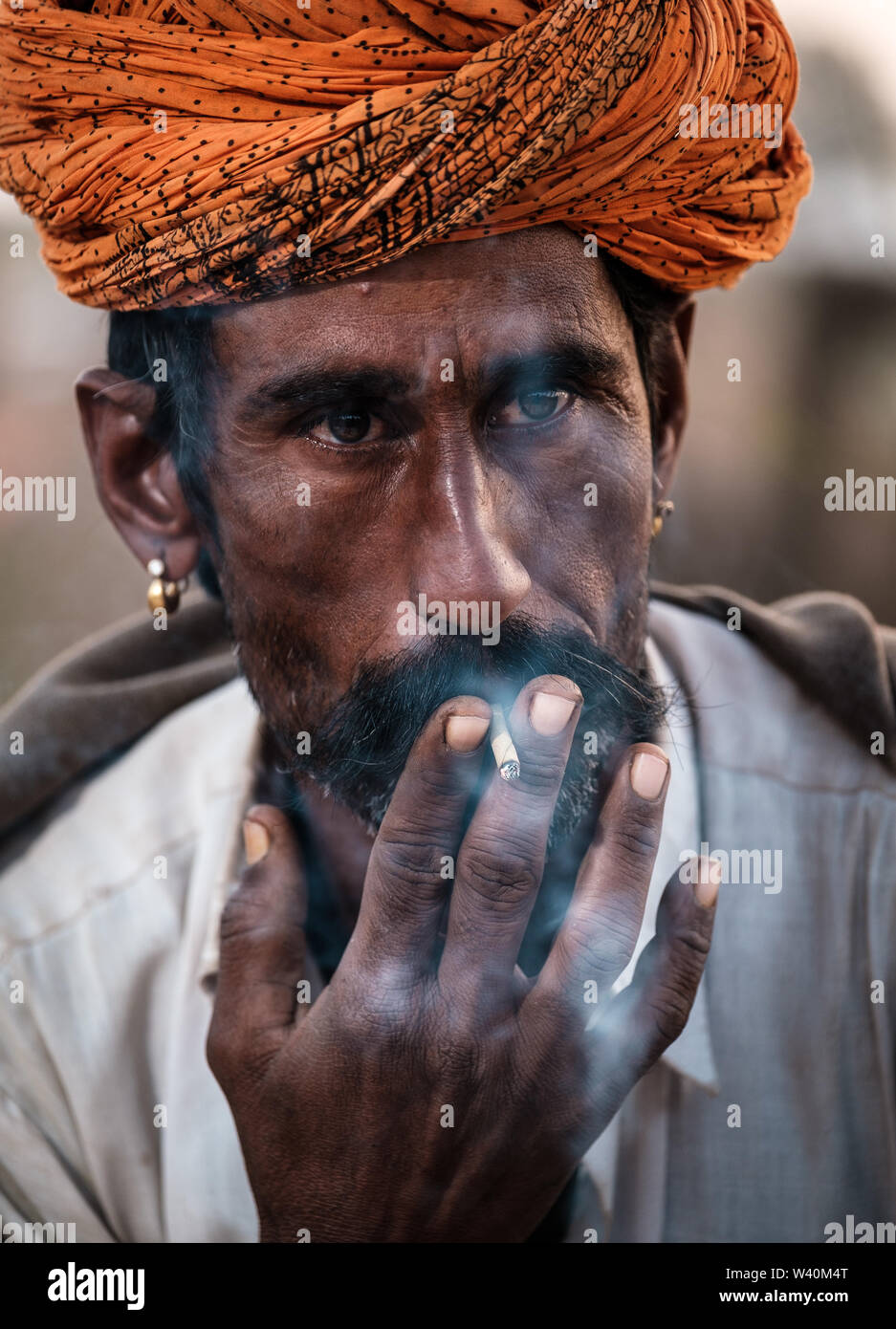 PUSHKAR, INDIA - CIRCA NOVEMBRE 2018: Cameleer fumare la mattina presto in Pushkar Camel Fair grounds. Si tratta di uno dei più grandi del mondo fiere di cammello. Foto Stock