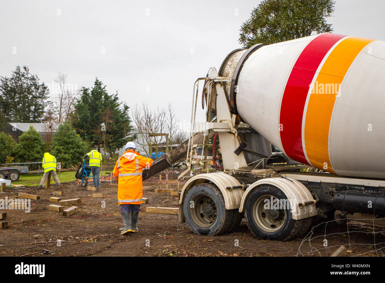 Annat, Canterbury, Nuova Zelanda, 19 Luglio 2019: Costruttori Cariola di cemento bagnato da un mescolatore concreto carrello per pali di fondazione in un edificio rurale sit Foto Stock