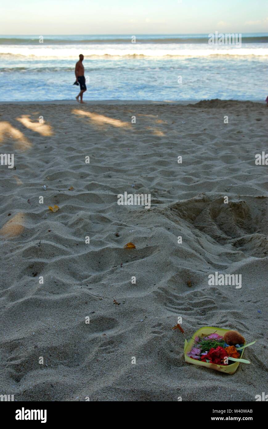 La spiaggia di Kuta Beach, Bali, Indonesia - Giugno 2019 : la gente a piedi su una spiaggia dove la gente mettere offrendo alla divinità Indù. Foto Stock