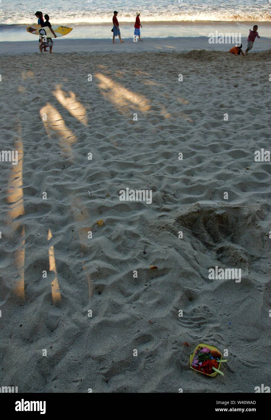 La spiaggia di Kuta Beach, Bali, Indonesia - Giugno 2019 : la gente a piedi su una spiaggia dove la gente mettere offrendo alla divinità Indù. Foto Stock