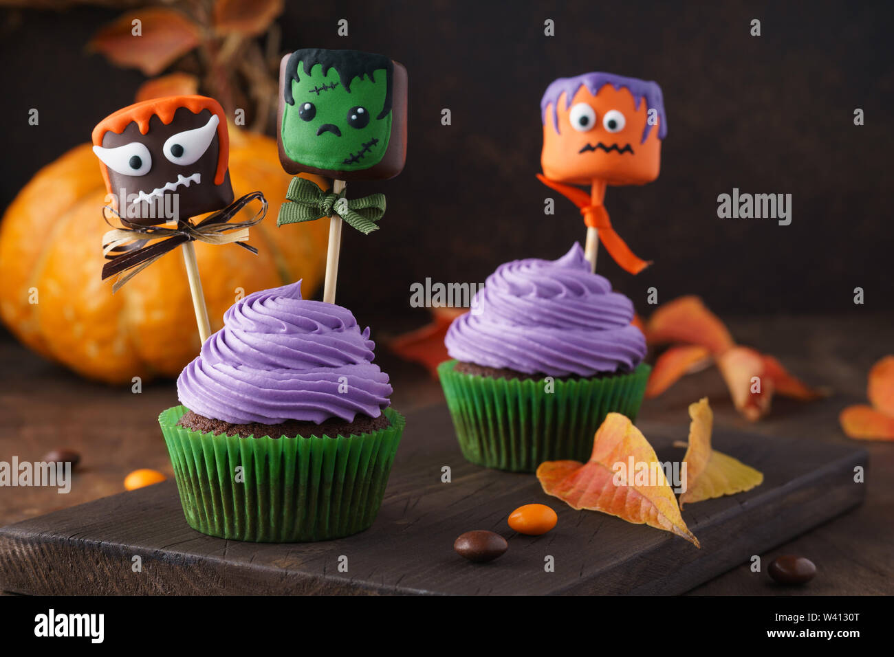 Festive Halloween tortine decorate con marshmallow in cioccolato o torta pops e caramelle. Funny monster faccia tratta. Foto Stock