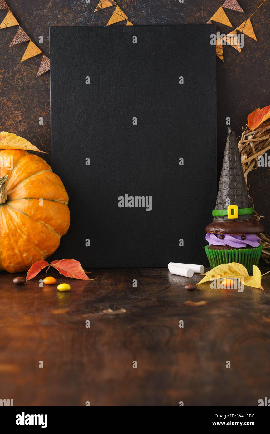 Caduta stagione festiva sfondo lavagna con la zucca, foglie e chicche di Halloween - caramelle e strega hat tortina. Vendita di Halloween mockup con vuoto Foto Stock