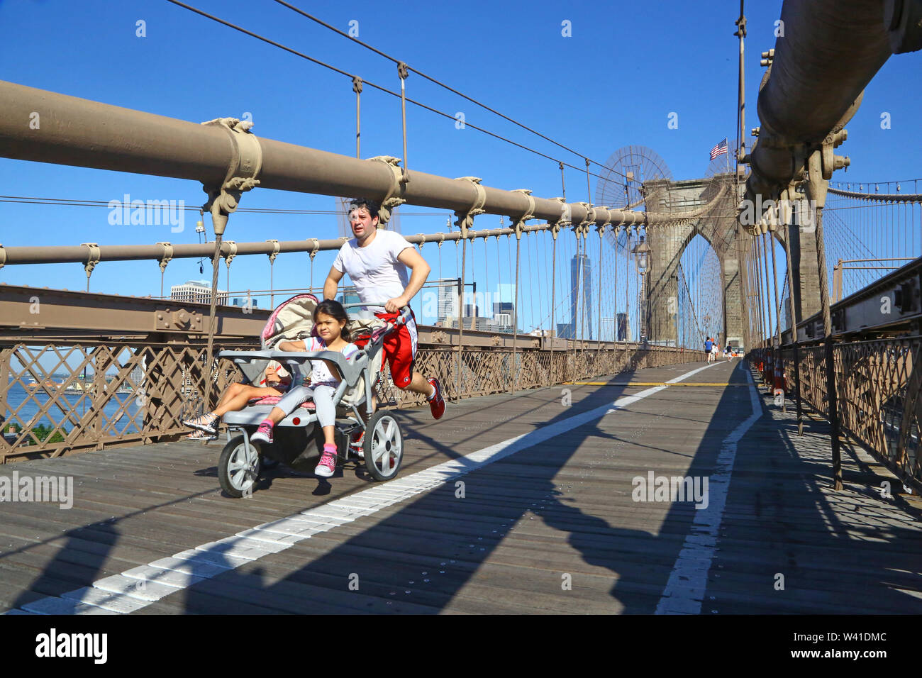 Ponte di Brooklyn a New York. Padre corre spingendo 2 bambini in un carrello Foto Stock