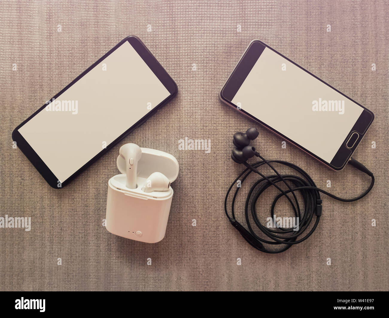 Confronto tra due telefoni, uno ha 3.5mm jack cuffie cablate vs auricolari wireless per la musica in ascolto. Vantaggi e svantaggi, opposta al contrario. Techno Foto Stock