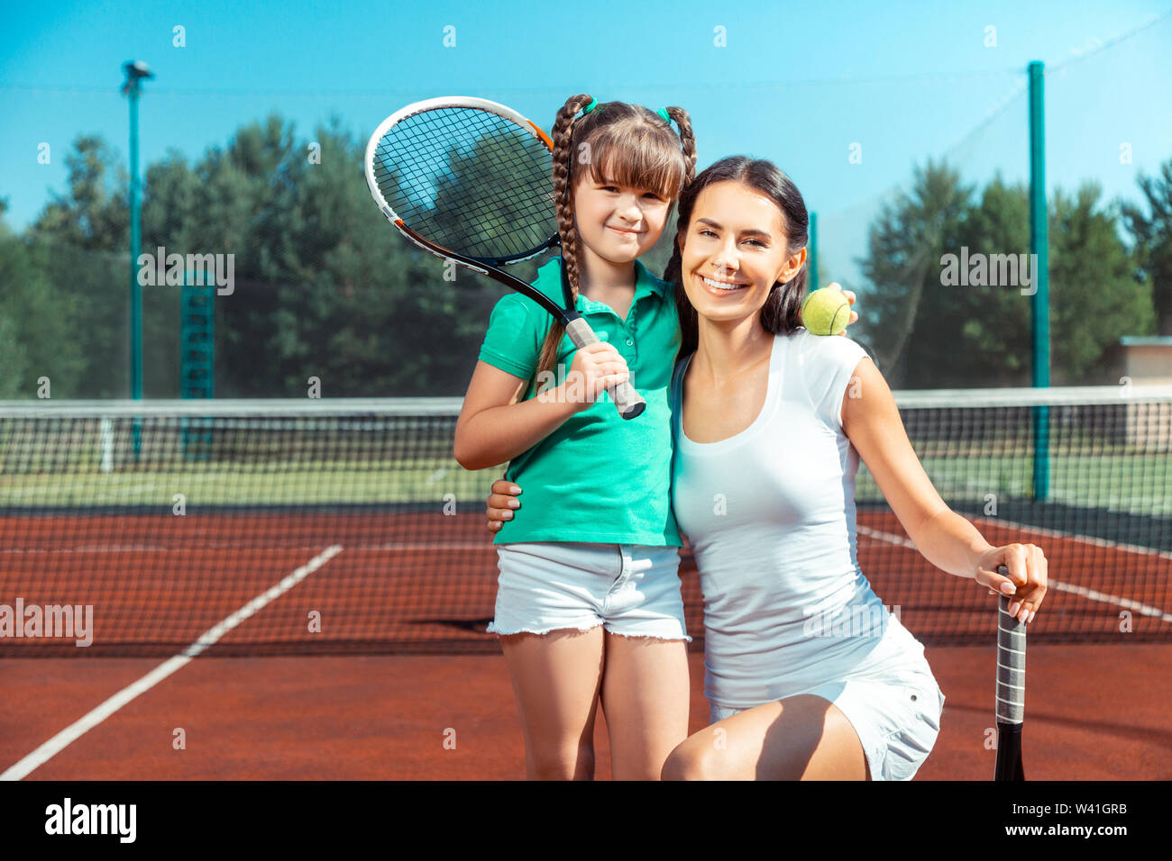 La mamma e figlia holding racchette da tennis e sorridente Foto Stock