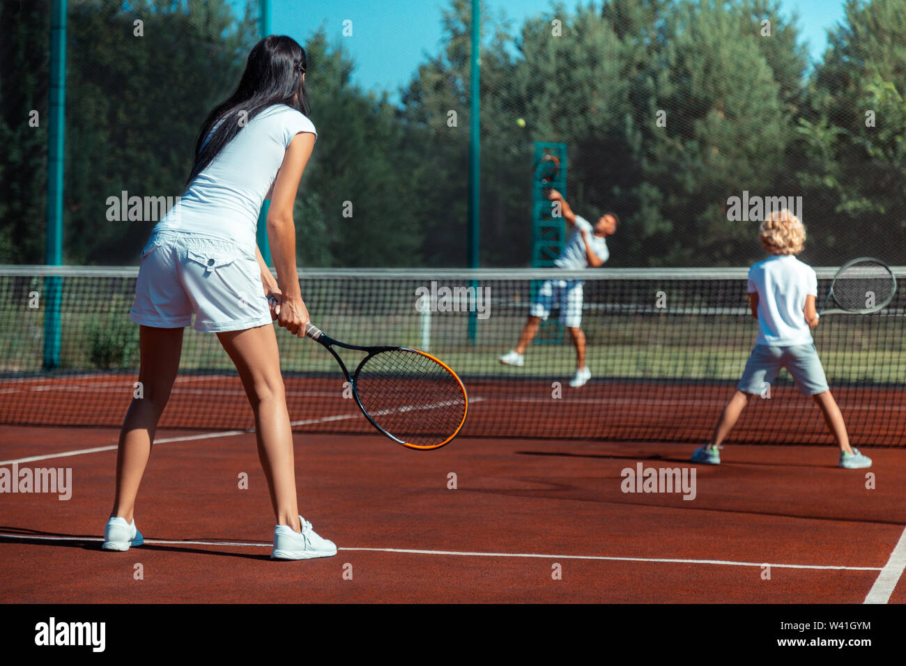Dai capelli scuri moglie giocando a tennis con mio marito e figlio Foto Stock