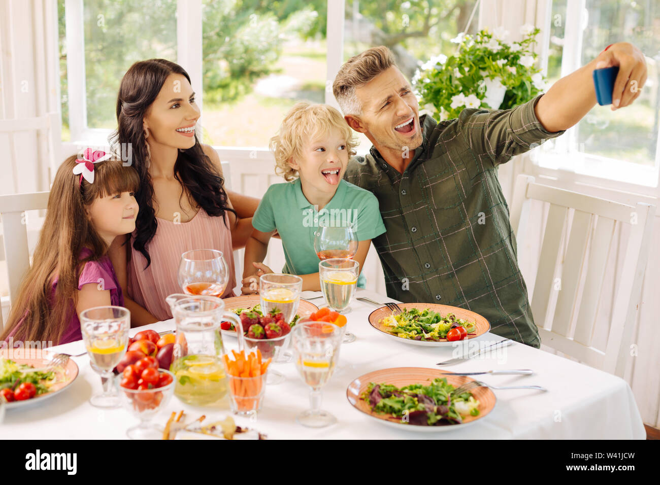 Famiglia rendendo selfie pur avendo il pranzo nella casa estiva Foto Stock