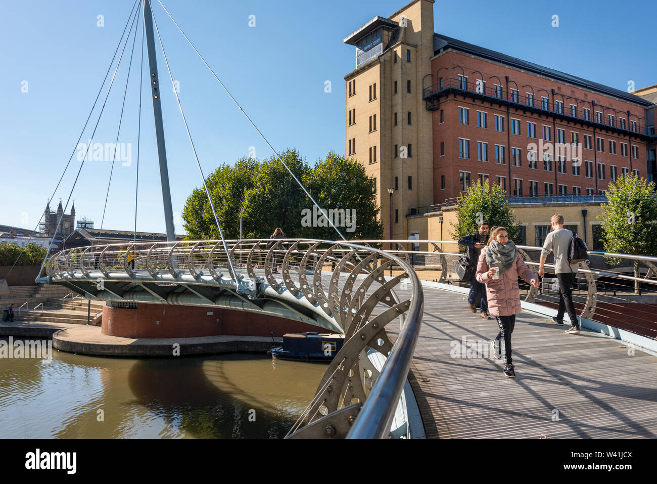 I pedoni attraversare a piedi il ponte di San Valentino su Floating Harbour con uno di Temple Quay edificio in background, Bristol, Regno Unito Foto Stock