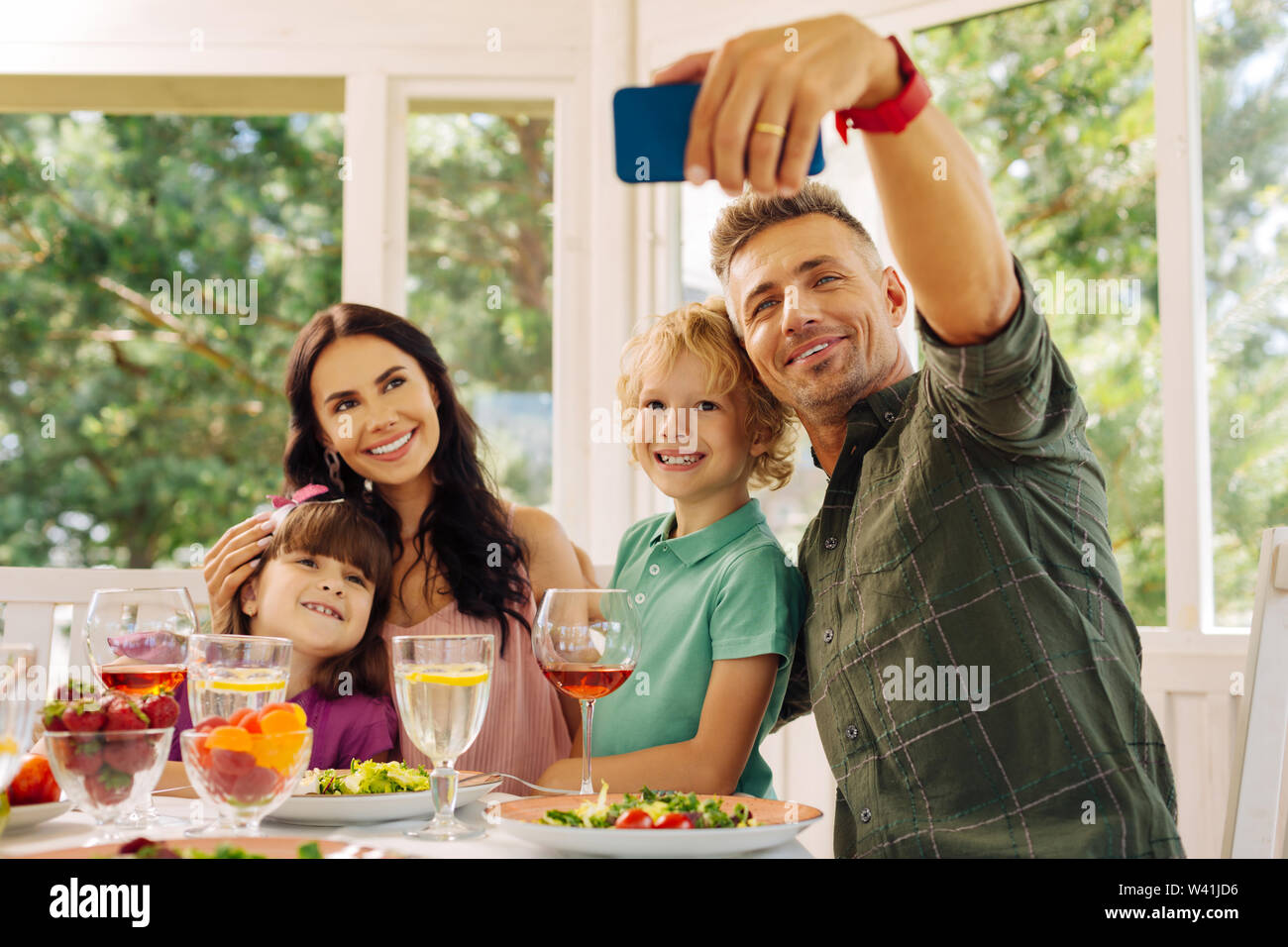 Il marito di prendere il suo smartphone mentre si effettua selfie con la famiglia Foto Stock