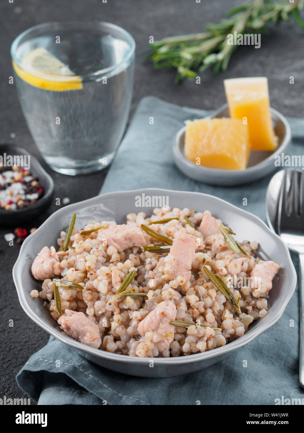 Materie del grano saraceno risotto con carne di pollo e il rosmarino servita parmigiano reggiano in lastra grigia su nero lo sfondo di cemento. Senza glutine e grano saraceno ricetta idee. Spazio di copia Foto Stock