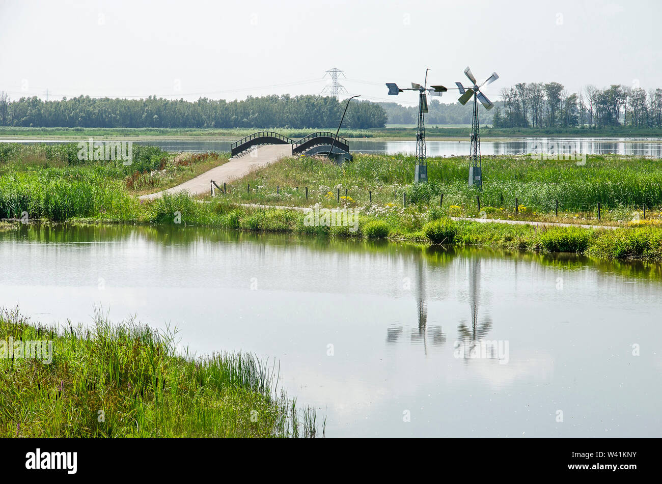 Due piccoli mulini a vento, un ciclo turistico via e un ponte in zona umida del Noordwaard sezione di Biesbosch parco nazionale nei Paesi Bassi su un Foto Stock