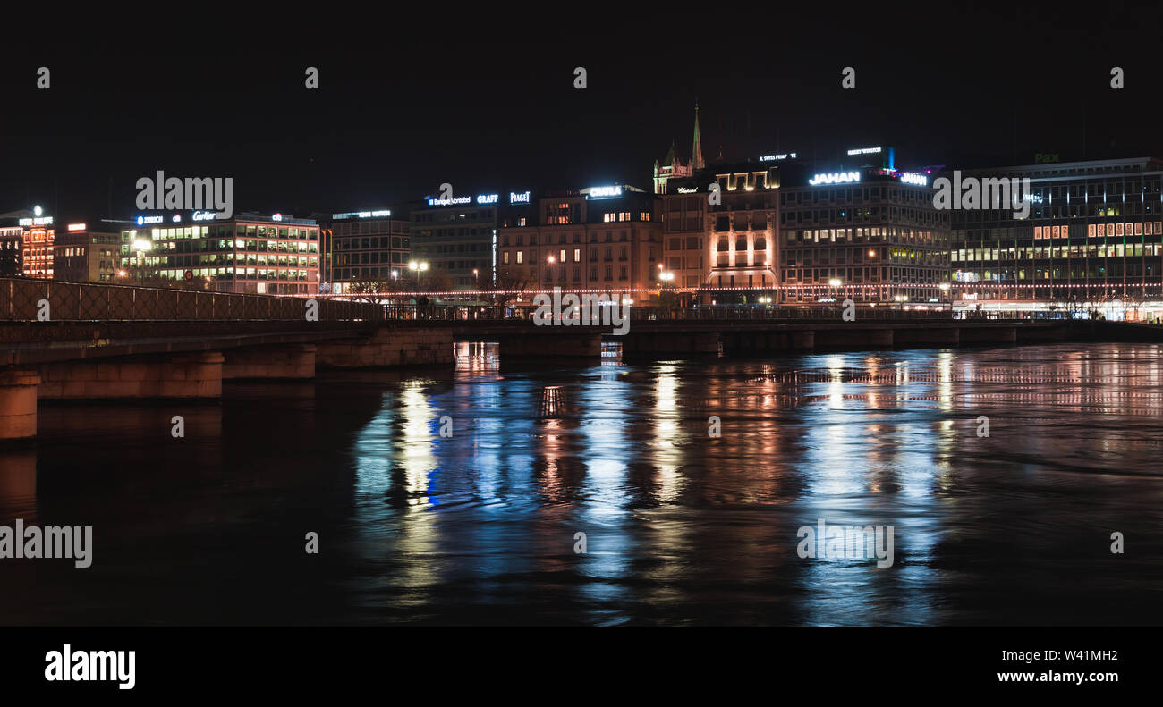 Ginevra, Svizzera - 24 Novembre 2016: notte paesaggio panoramico con facciate illuminate su un lungo fiume nella città di Ginevra. Illuminata di Pont de la Mach Foto Stock