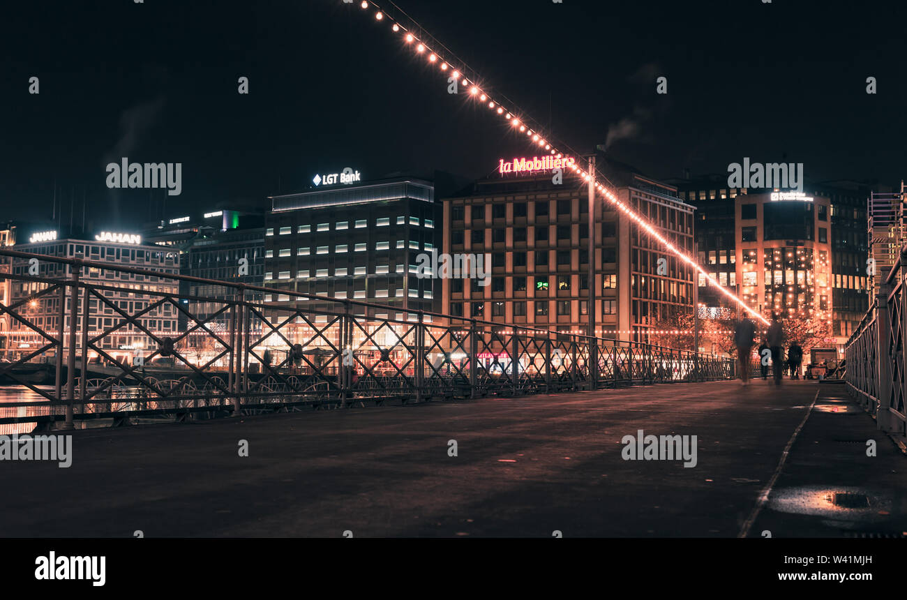 Ginevra, Svizzera - 24 Novembre 2016: notte paesaggio panoramico con facciate illuminate su un lungo fiume nella città di Ginevra. La gente comune a piedi su t Foto Stock