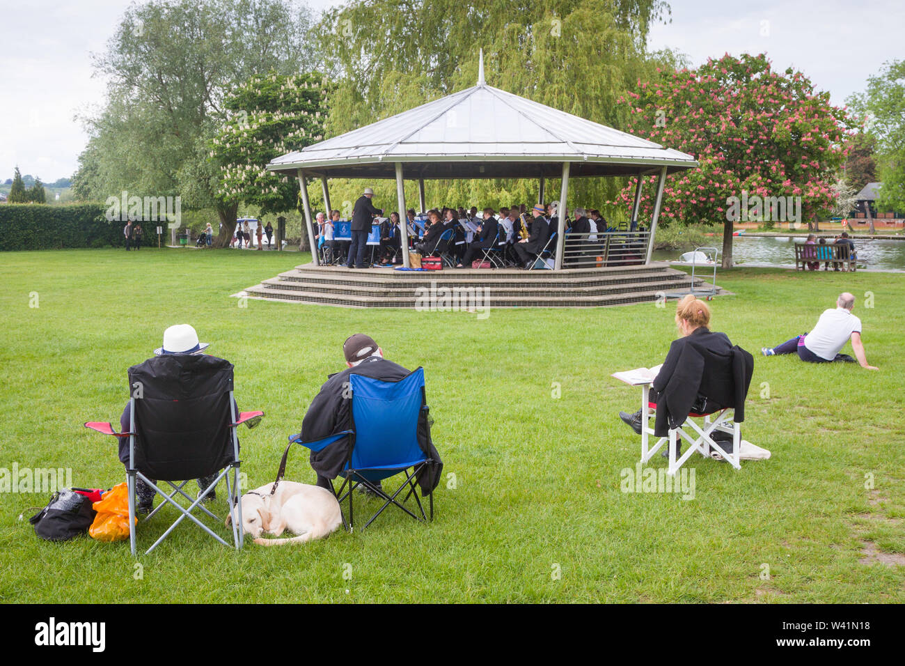 Seduta nel parco al mulino Prati, Henley-on-Thames, ascoltando il brass band suonare sul palco per spettacoli Foto Stock