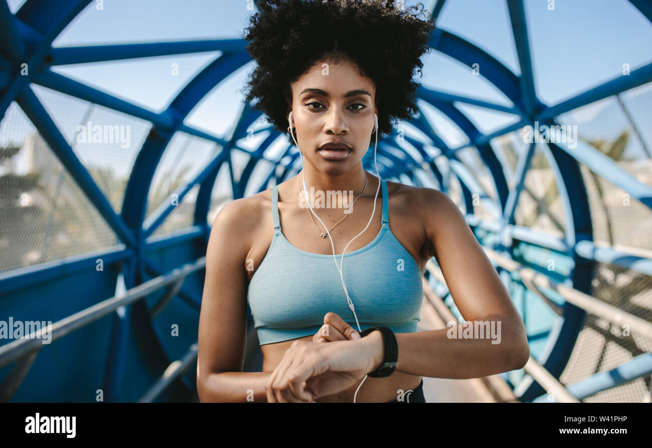 Giovane donna fitness con smart watch guardando la fotocamera. Sportive controllo impulso su smart watch app fitness. Foto Stock