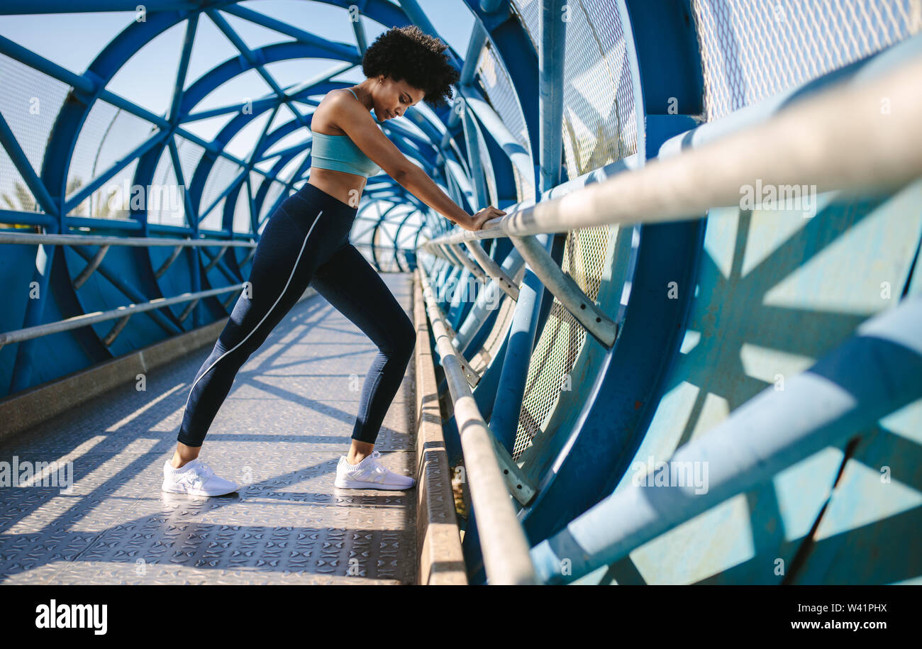 Donna Fitness facendo stretching con il supporto del ponte della ringhiera. Atleta femminile facendo esercizi di stretching. Foto Stock