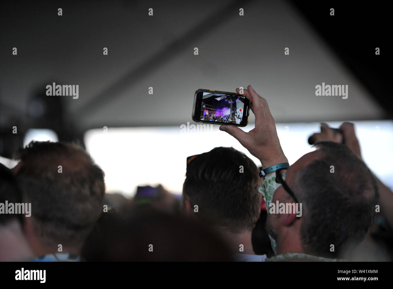 Un pubblico membro prende una foto di George Ezra come suona un segreto impostato per segnare il decimo anniversario del granaio sulla Farm Music Festival Foto Stock