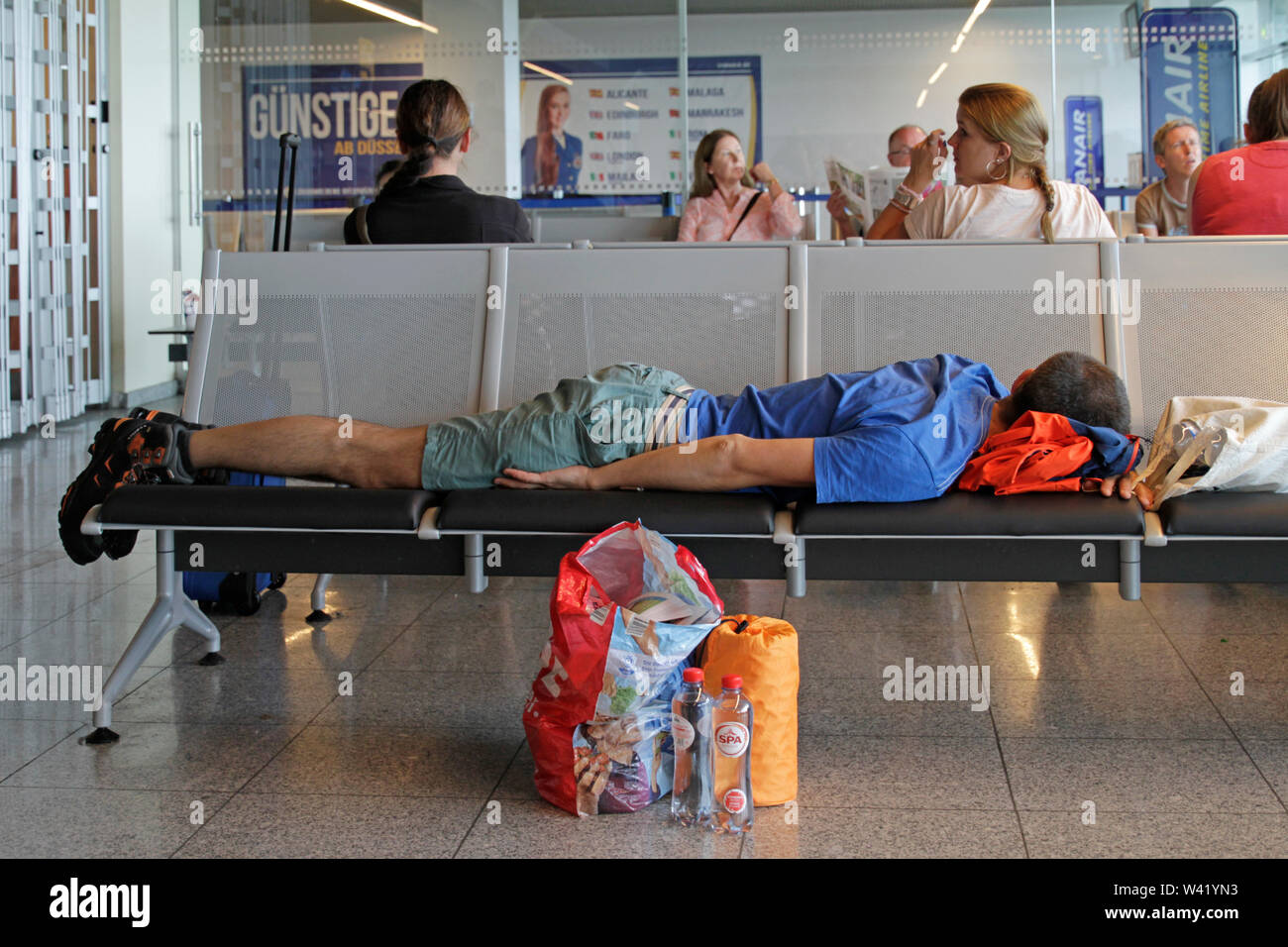 Düsseldorf, Germania - 23 Giugno 2019: Passeggeri dormire su una panchina alla porta di aeroporto a seguito di un ritardo del volo. Foto Stock