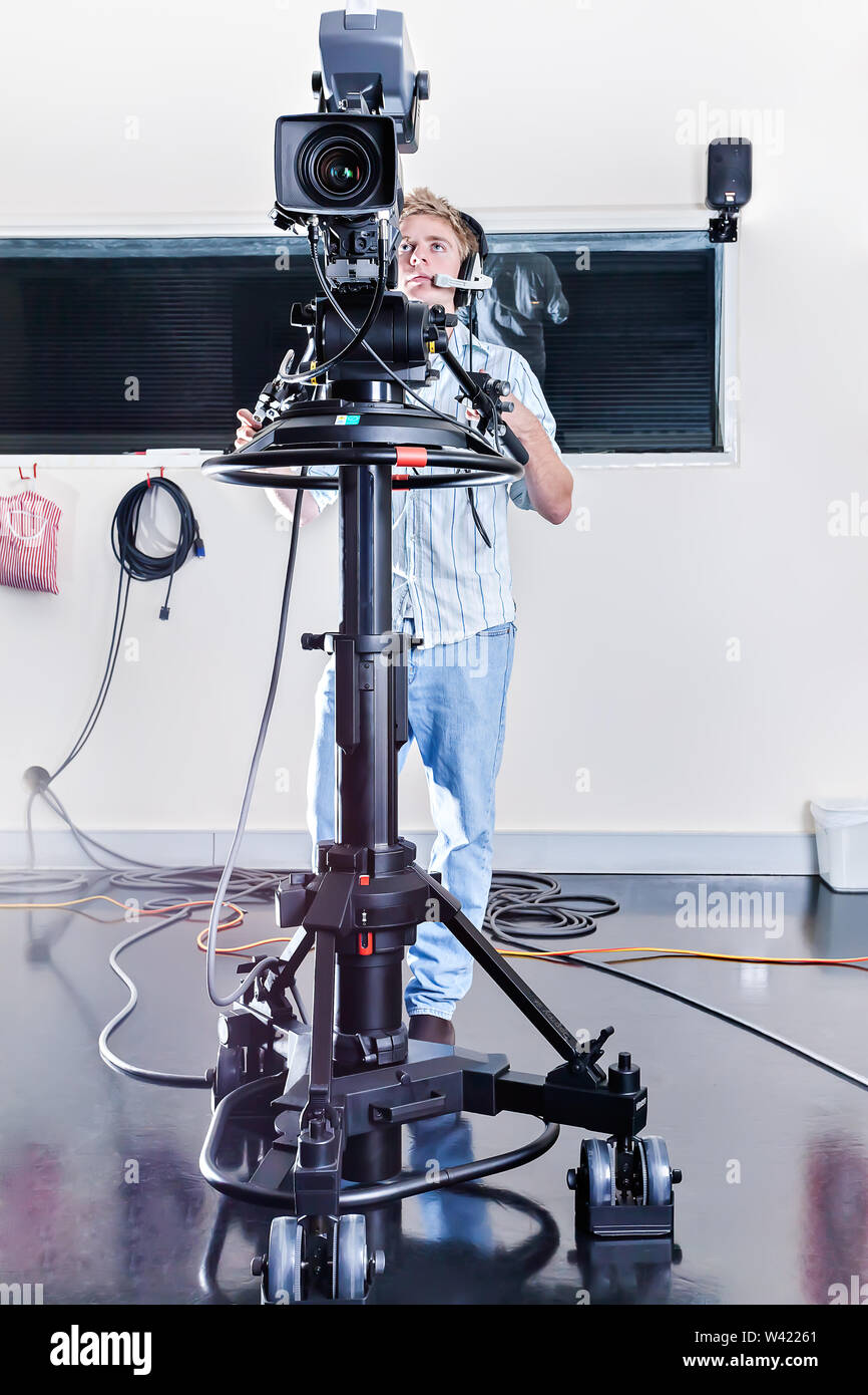 Guy è operativo un enorme studio la fotocamera in una stanza e la configurazione per la registrazione e la trasmissione Foto Stock