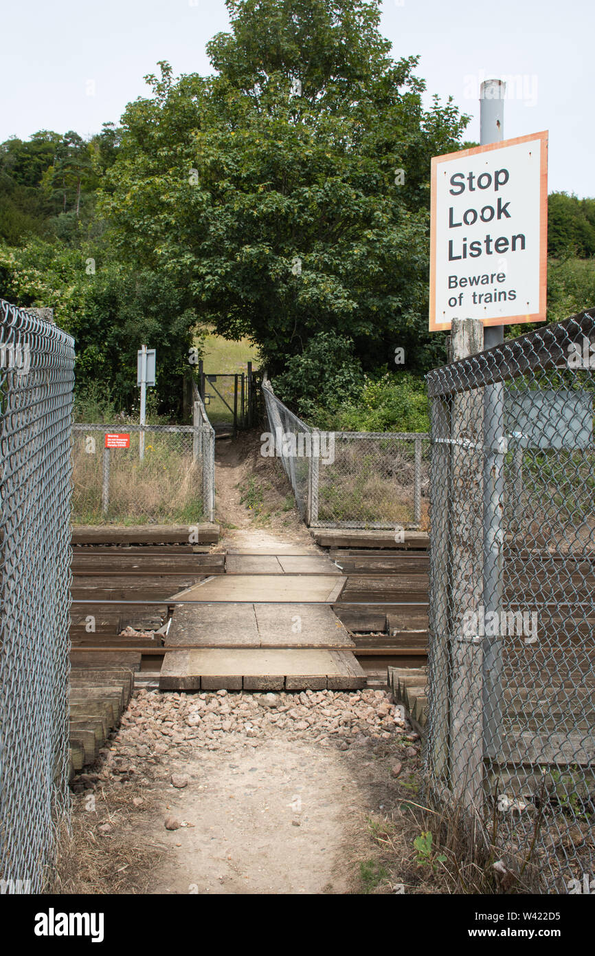 Il percorso attraversa un binario ferroviario con un avviso di sicurezza segno, smettere di cercare di ascoltare, attenzione ai treni, REGNO UNITO Foto Stock