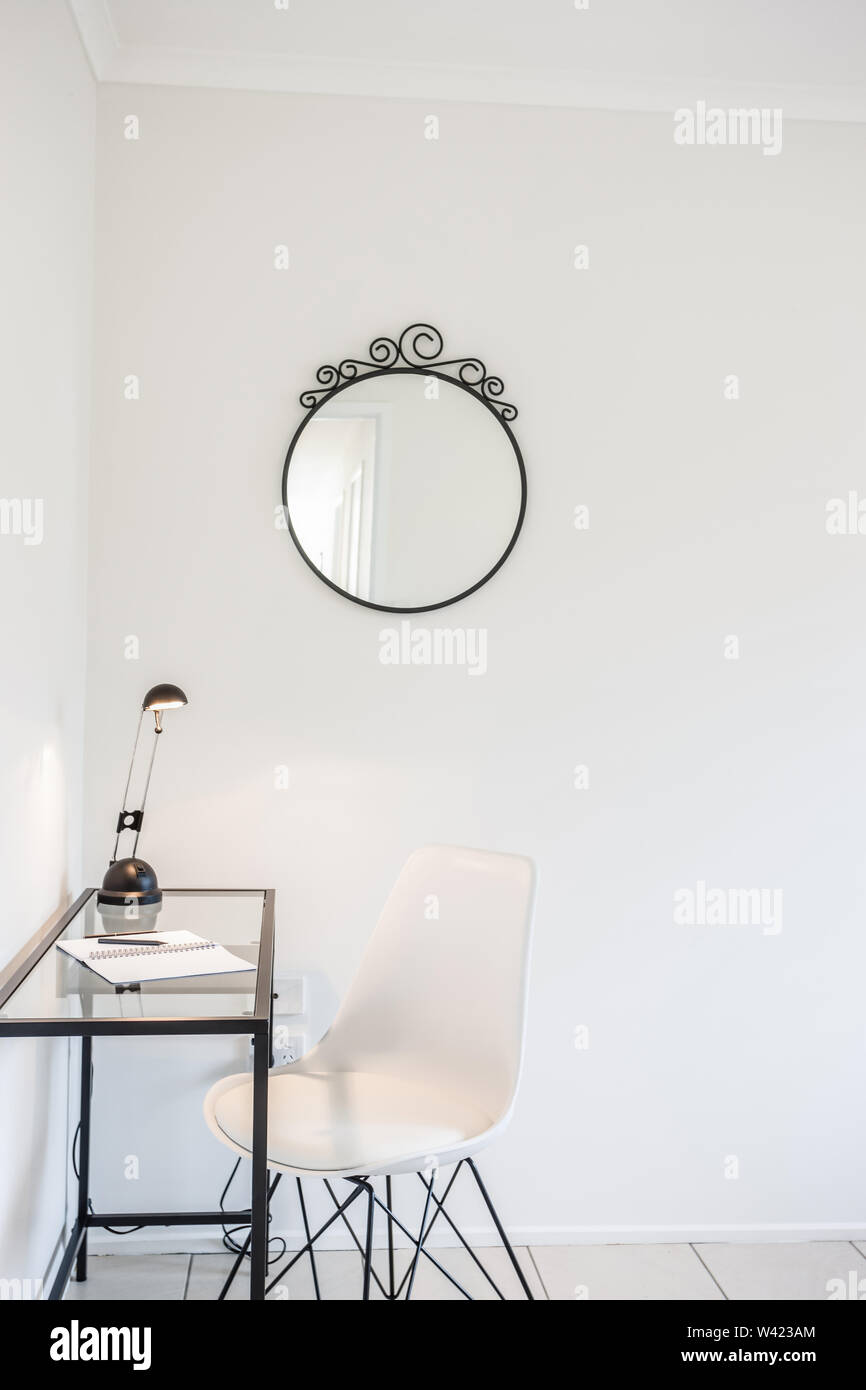 Vista pittoresca di una sala studio dotata di uno specchio, un tavolo con lampada su di essa e una sedia Foto Stock