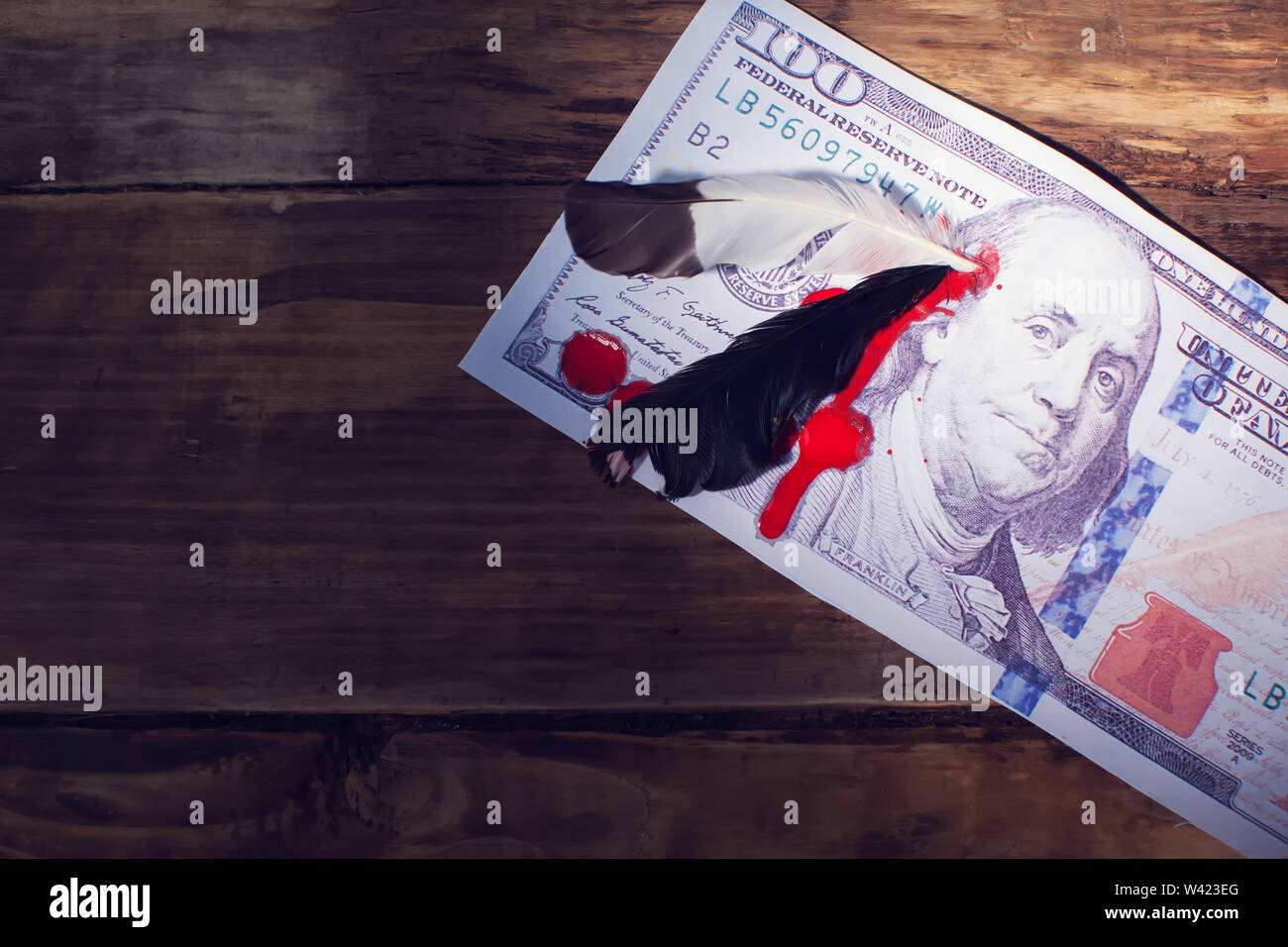 Un centinaio di dollari con piuma in testa del presidente e di sangue vicino la foto. Pelle rossa concetto di guerra Foto Stock