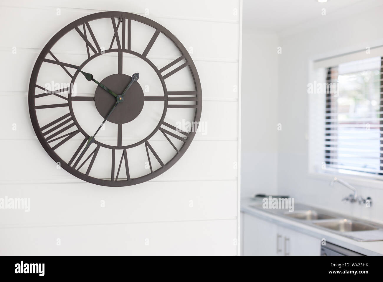 Vista di un orologio da parete grande posto al di fuori della zona cucina con uno stile contemporaneo e il numero romano ora marcatori Foto Stock