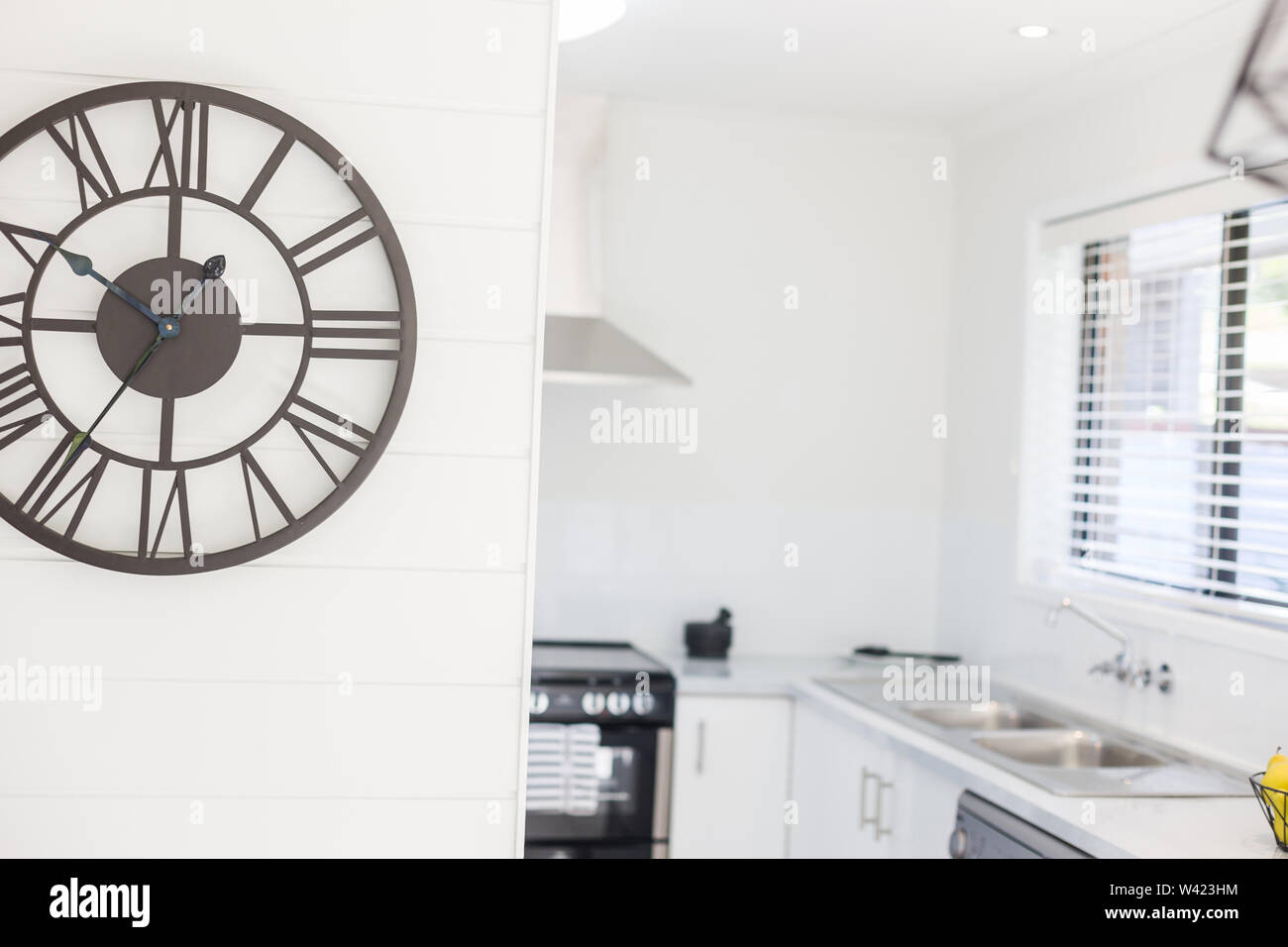 Vista di un orologio da parete grande posto al di fuori della zona cucina con uno stile contemporaneo e il numero romano ora marcatori Foto Stock