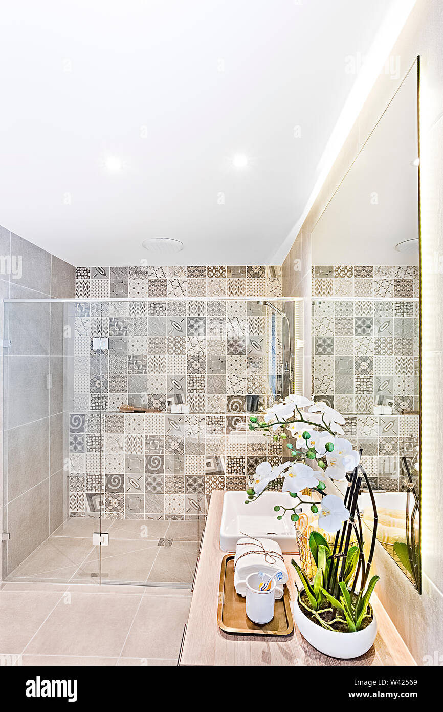 Bagno interno con parete di pattern area doccia e decorazioni floreali tra  cui una tazza e