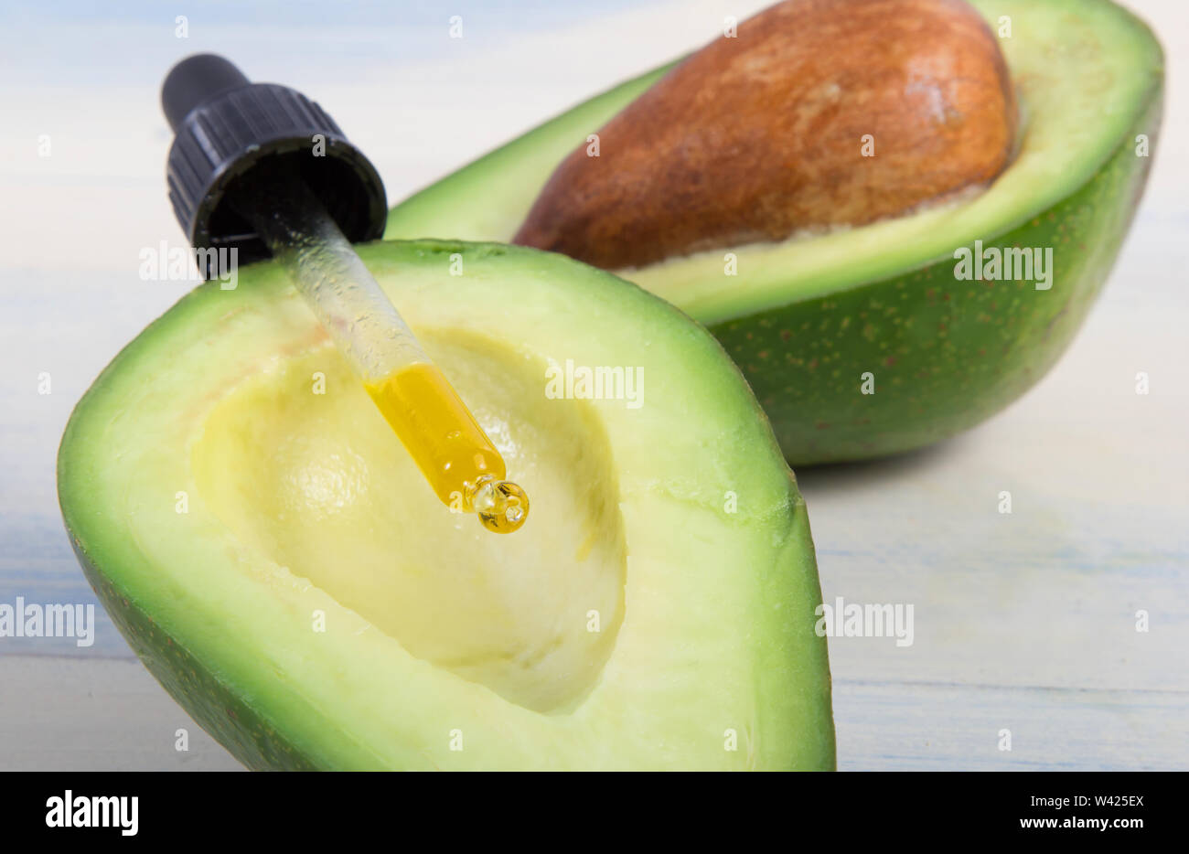 Frutto di avocado e olio su sfondo lucido Foto Stock