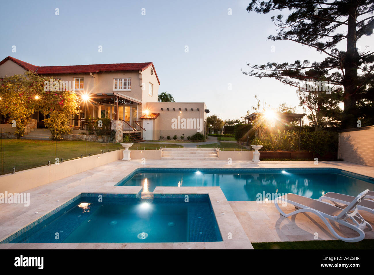 Moderna piscina area con luci da giardino di un palazzo, il Waterside è diviso in due parti e vi è una sedia per il relax, un alto albero può Foto Stock