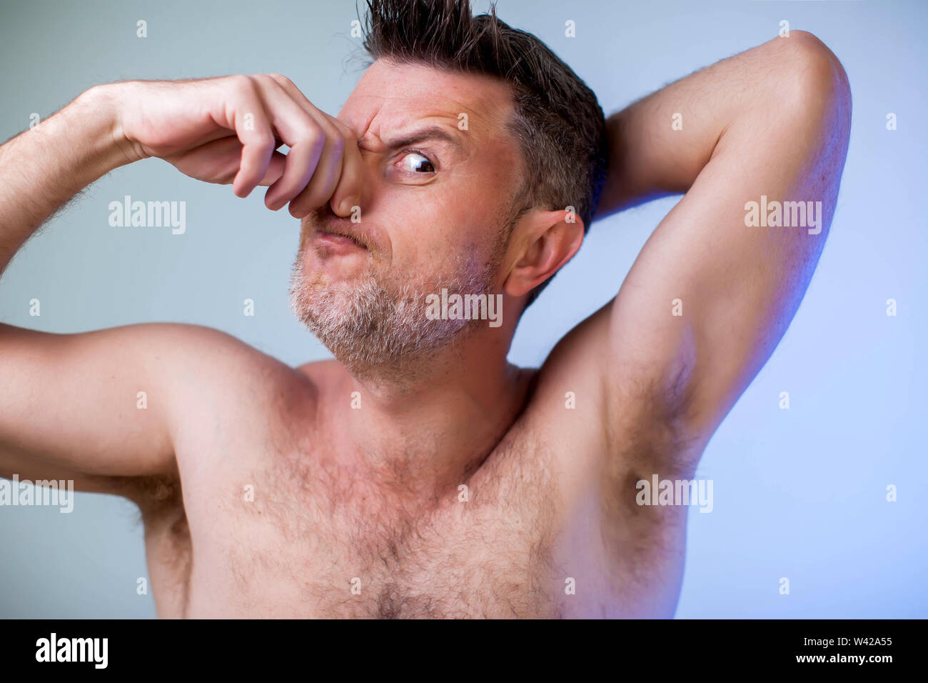Close up ritratto di Giovane uomo, odorando la sua ascella, sensazione di cattivo odore, vuole fare una doccia, esigenze antitraspiranti Foto Stock
