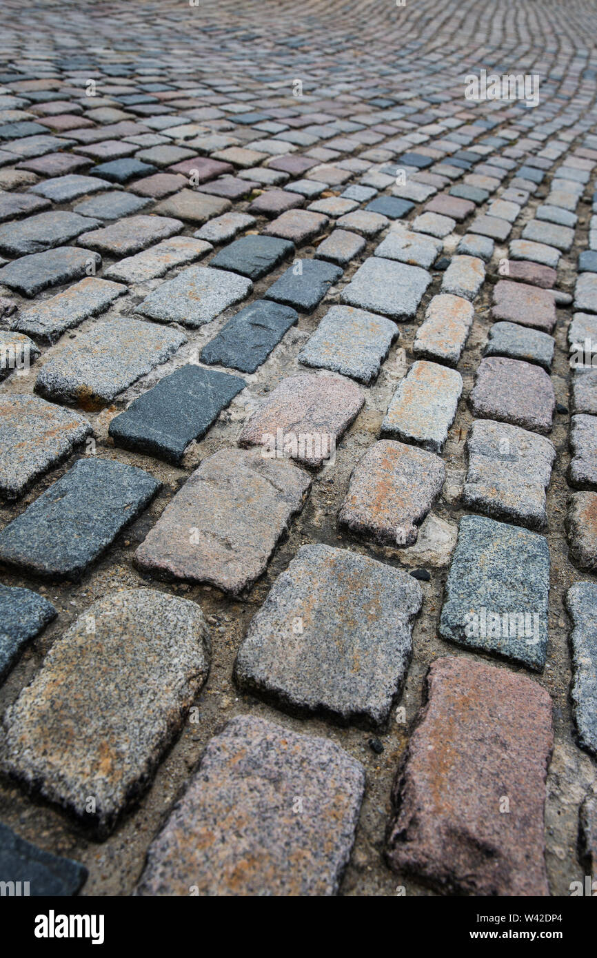 Un frame completo immagine di sfondo delle righe di acciottolato che si protende nella distanza su una strada di ciottoli con spazio di copia Foto Stock