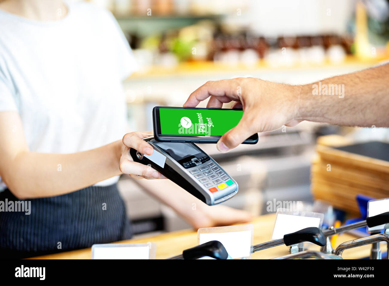 Cameriera holding card reader POS per l uomo di pagare tramite smartphone Foto Stock
