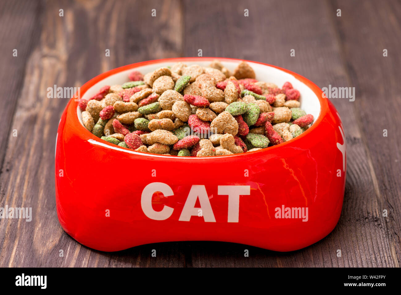 Close-up rosso gatto ciotola con cibo secco sul pavimento a casa Foto Stock