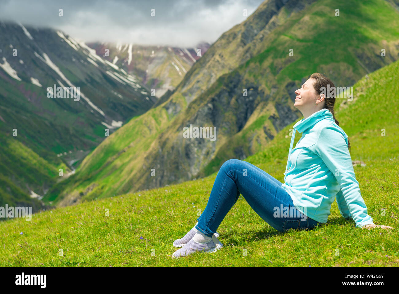 Donna felice in appoggio e ammirando le montagne in campagna per il Caucaso Foto Stock