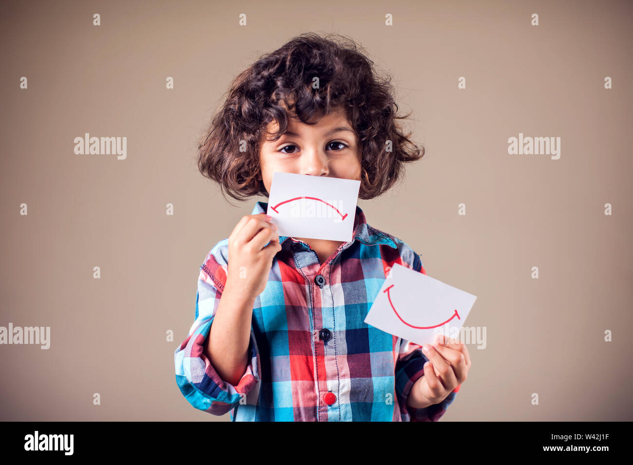 Kid boy selezionare tra positivo e negativo di espressioni. I bambini e le emozioni concetto Foto Stock