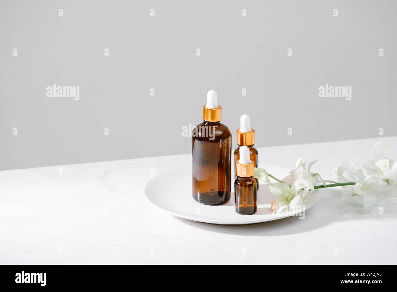 Impostazione di Spa con orchidee e olio essenziale in una bottiglia di vetro, aromaterapia concept Foto Stock