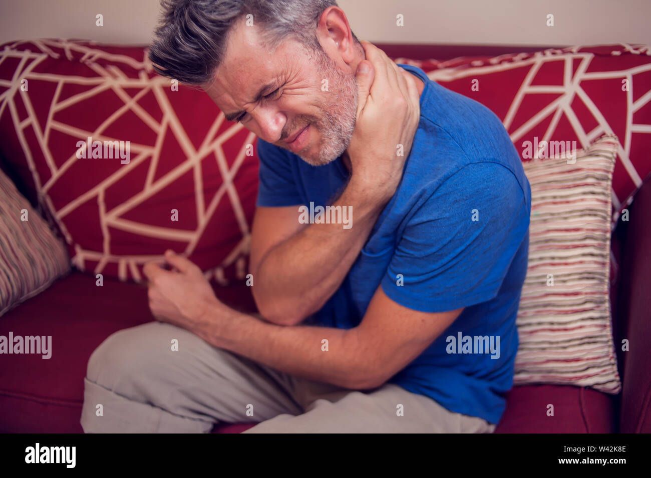 L'uomo sente forte dolore al collo a casa. La gente, la sanità e la medicina concept Foto Stock