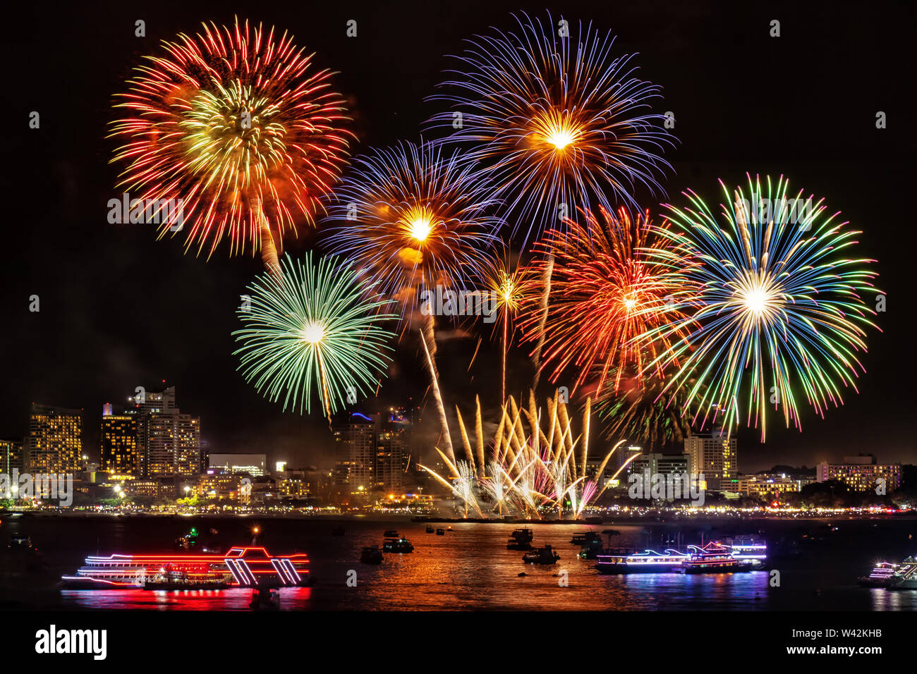 Festive coloratissimi fuochi d'artificio illuminano il cielo sopra la città di notte di scena per il festival di vacanza e di celebrazione sfondo Foto Stock