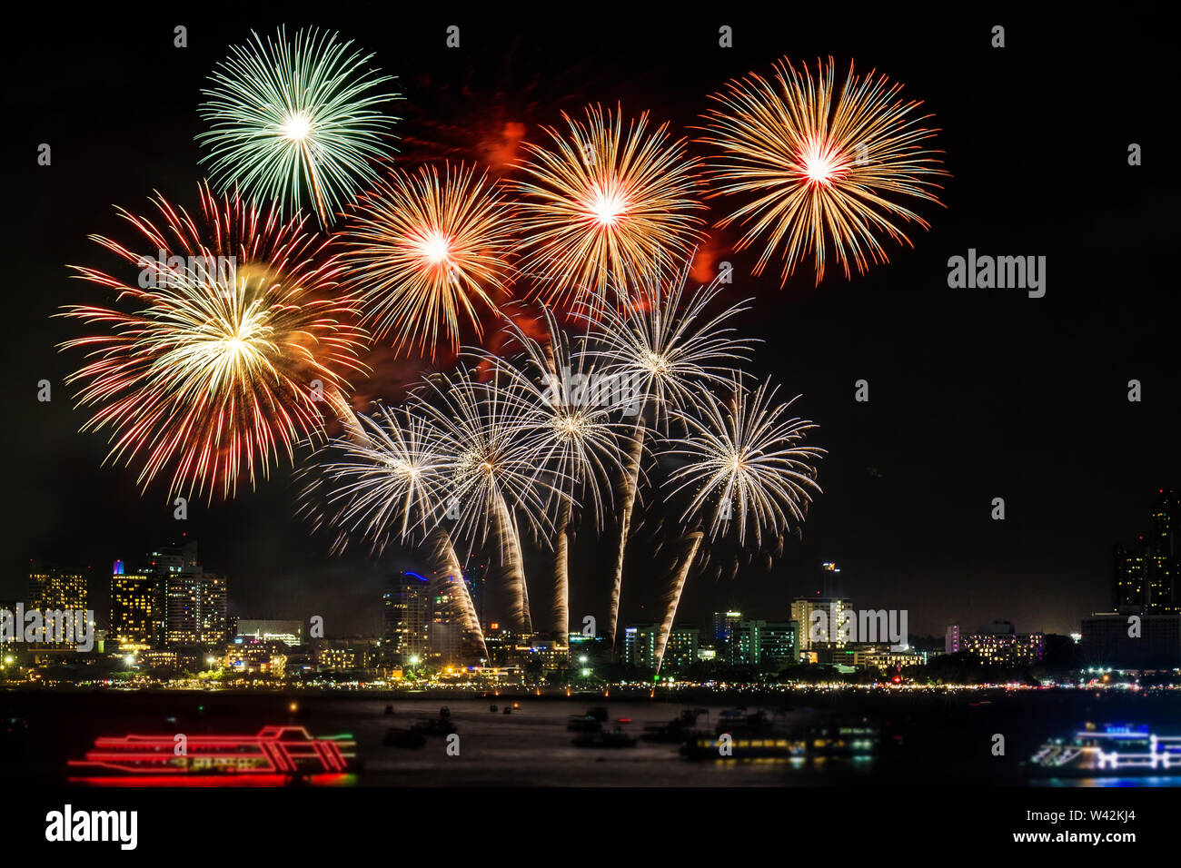 Festive coloratissimi fuochi d'artificio illuminano il cielo sopra la città di notte di scena per il festival di vacanza e di celebrazione sfondo Foto Stock