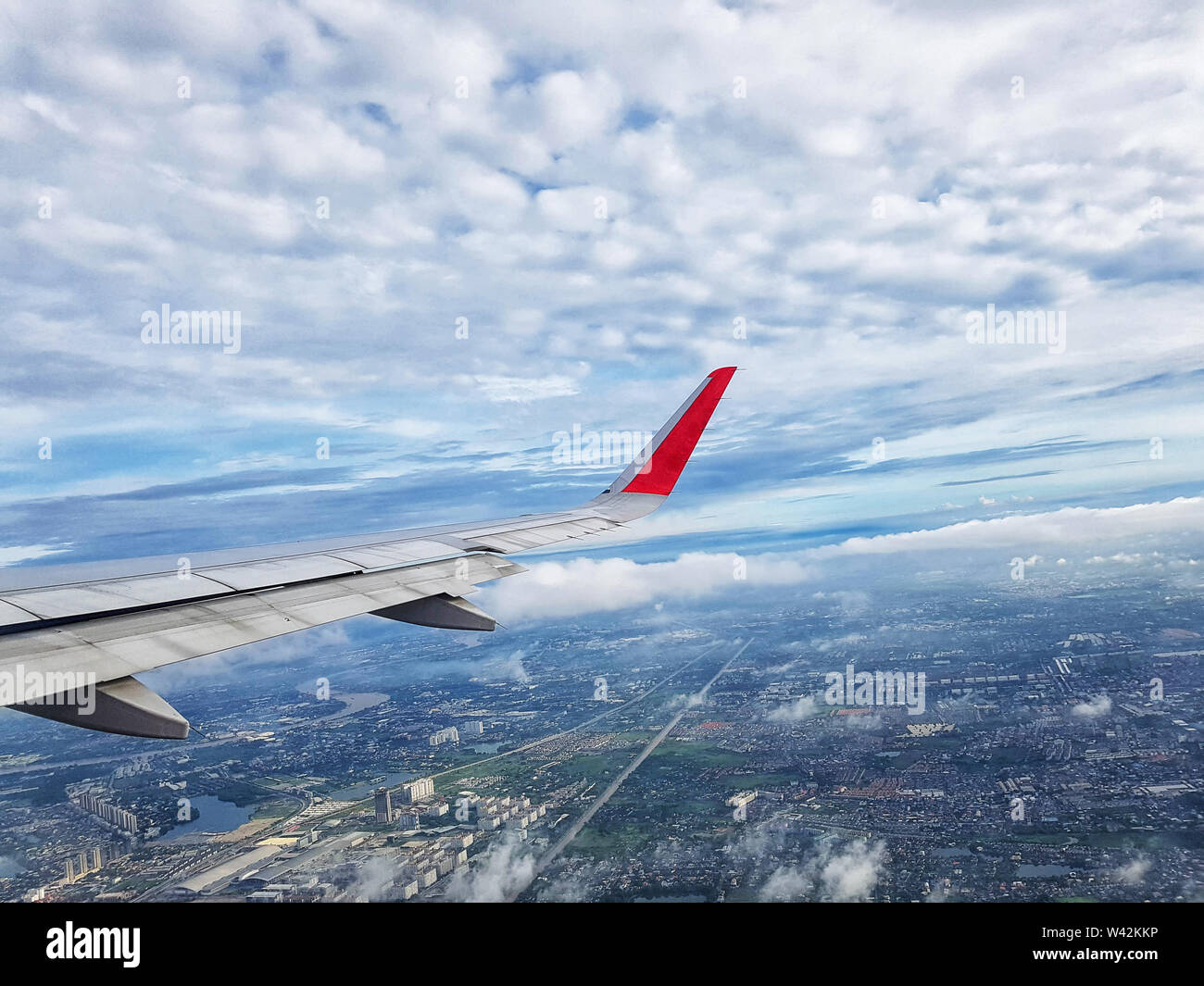Vista sulla città con le nuvole e il cielo come visto attraverso la finestra di un aeromobile. viaggi e concetto di vacanza Foto Stock