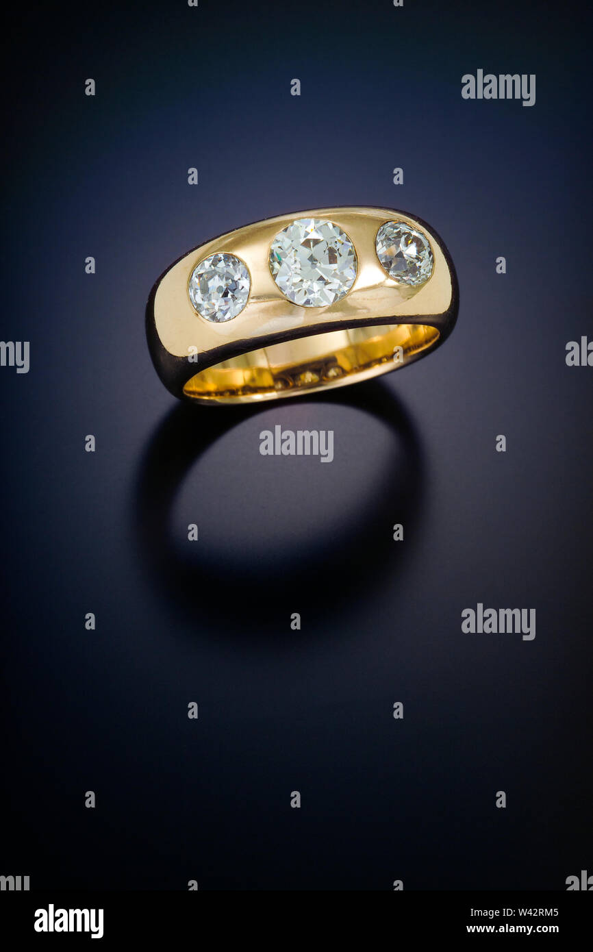 Tre grandi diamanti a taglio brillante sono a filo in un antiquariato a cupola oro lucido band. Foto Stock