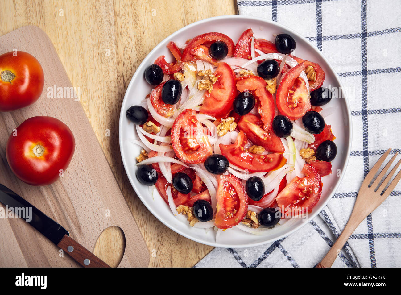 Gustosa insalata di pomodoro con cipolla e olive nere sulla piastra. Cucina mediterranea. Vista superiore Foto Stock
