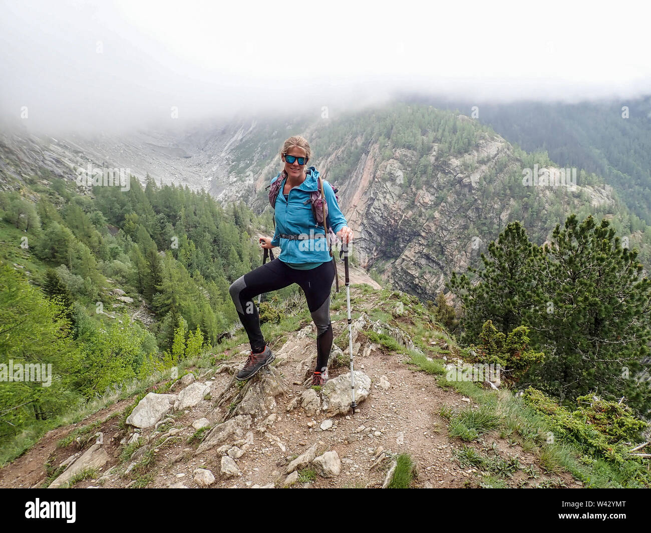 Donna escursionista con occhiali da sole in posa sulla cima di una collina nel torbido Francia Foto Stock