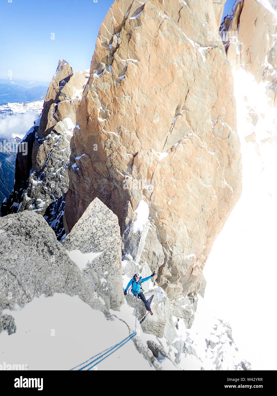 Donna alpinista lampeggia in segno di vittoria mentre sul rappel nelle Alpi francesi Foto Stock