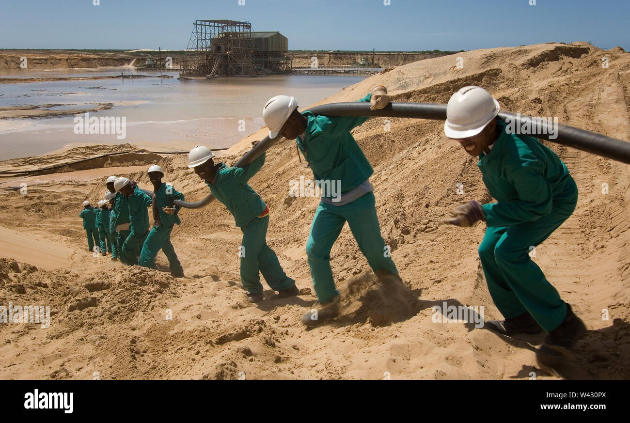 Estrazione, gestione e trasporto di sabbie minerali di titanio. Team di manutenzione che posa nuovi cavi di alimentazione sul lato del laghetto di estrazione per impianti umidi dietro. Foto Stock